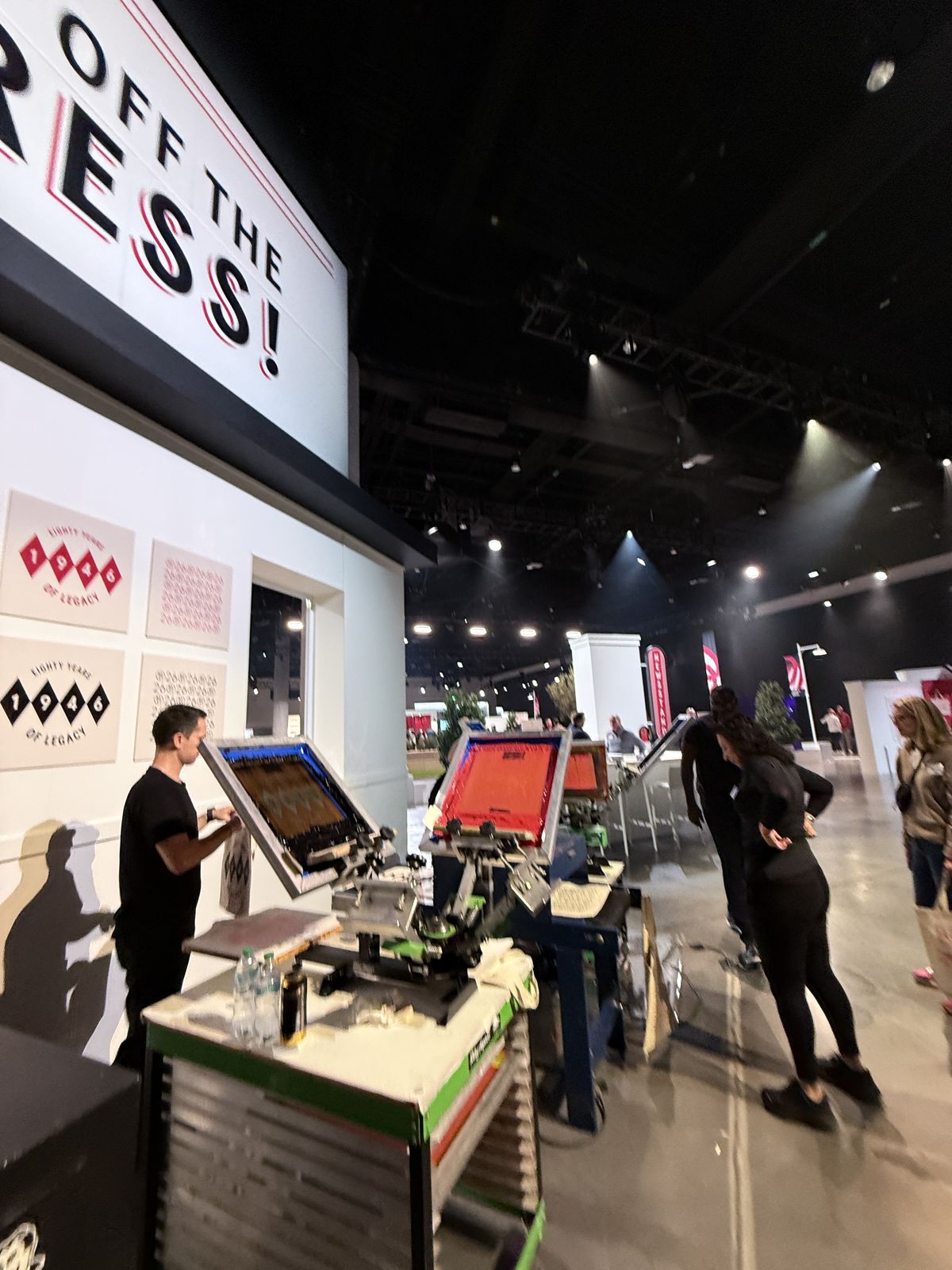 Live customization station on a convention floor with staff working at presses beneath a large Off The Press sign